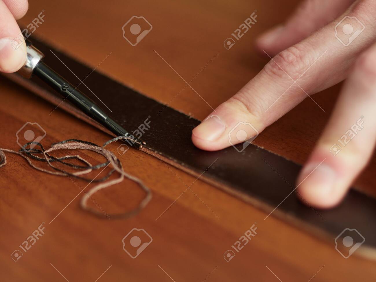 Chamfering with a leather belt by a tanner. - 126245931 Chamfering with a leather belt by a tanner. - 126245931