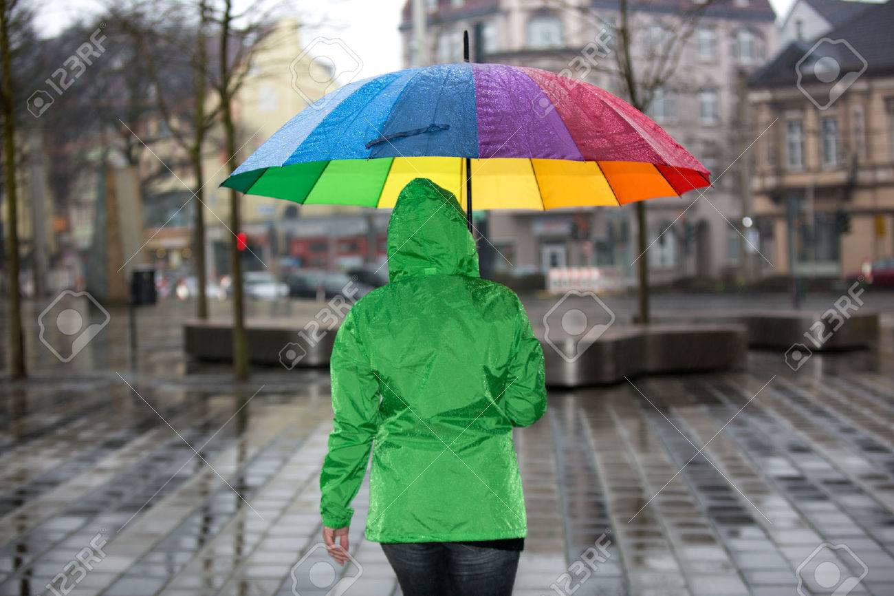 Una Mujer Está Caminando A De La Lluvia Con Un Paraguas Y El Impermeable Verde De La Ciudad. Fotos, Retratos, Imágenes Y Fotografía De Archivo De Derecho. Image 39482272.
