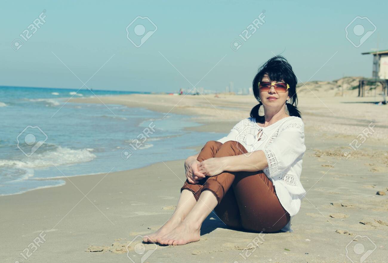 Old Woman Walking On The Beach Stock