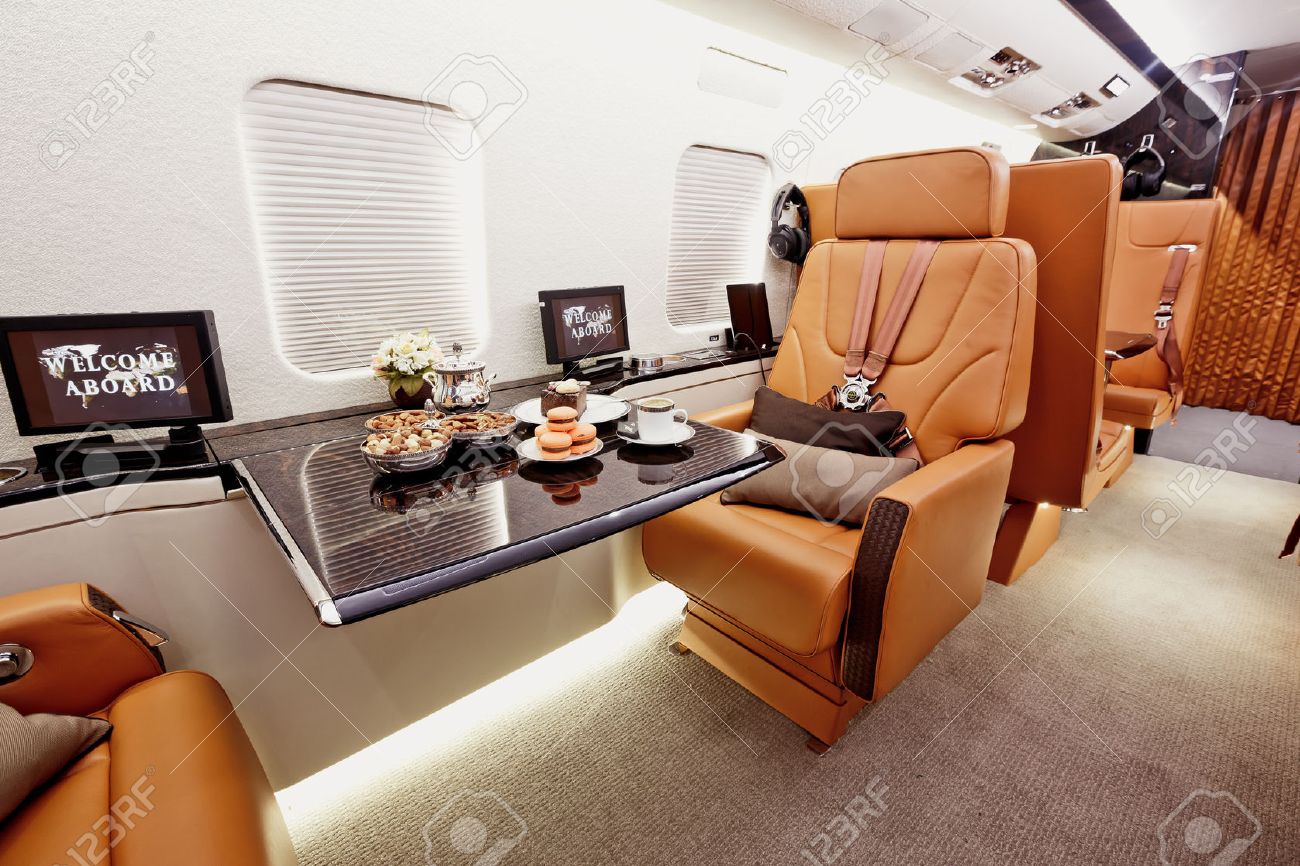 private plane interior with wooden tables and leather seats stock