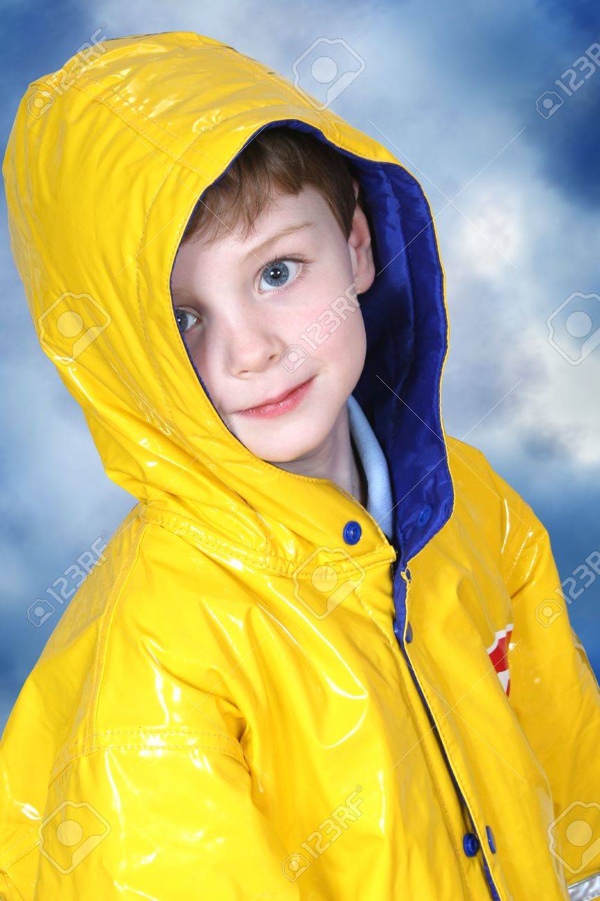 Cuatro años chico con grandes ojos azules en un chubasquero amarillo contra un azul oscuro moteado