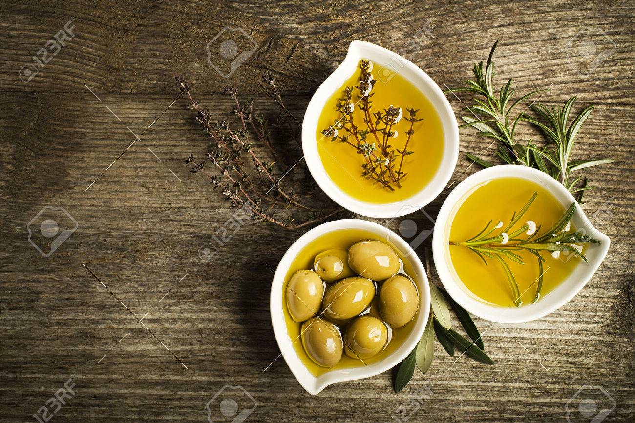 Olive oil with fresh herbs on wooden background. - 50122488 Olive oil with fresh herbs on wooden background. - 50122488