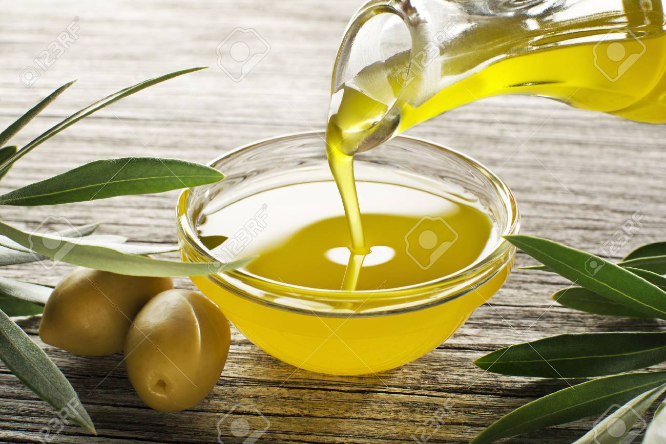 Bottle pouring virgin olive oil in a bowl close up - 61041236 Bottle pouring virgin olive oil in a bowl close up - 61041236