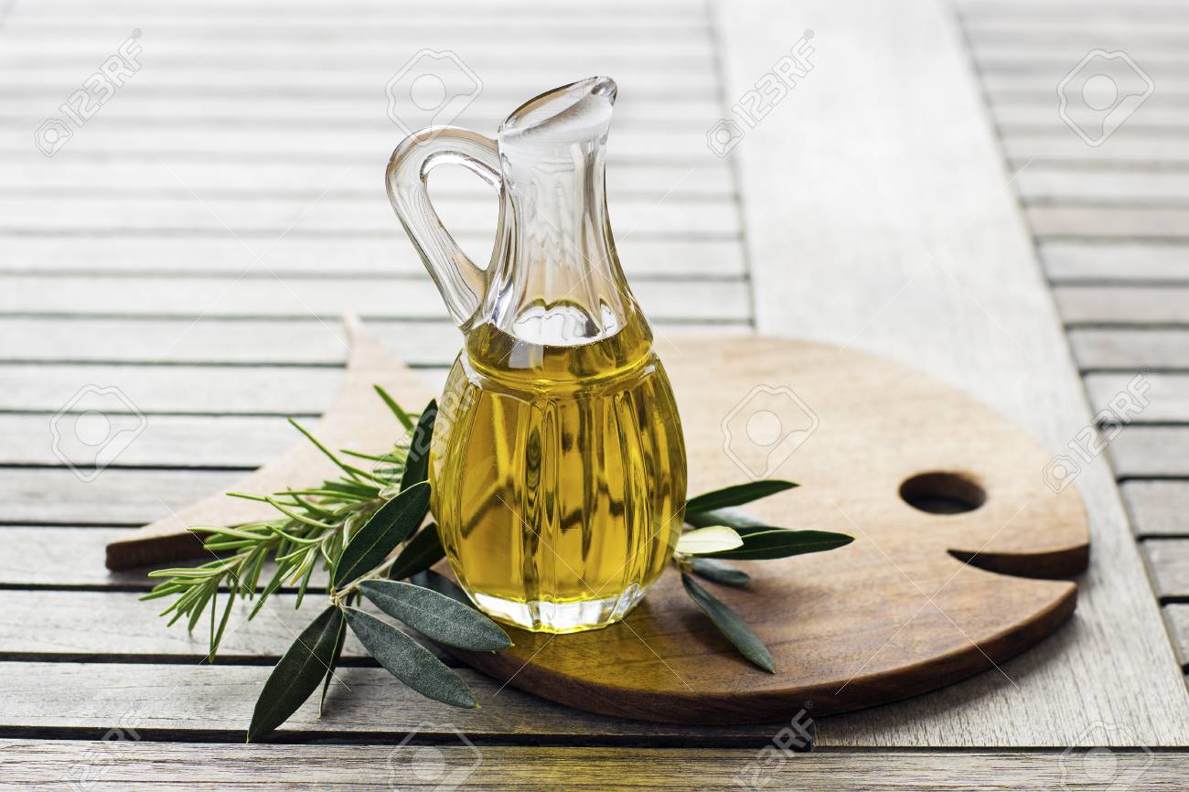 Olive oil with herbs and branch on wooden background - 90003158 Olive oil with herbs and branch on wooden background - 90003158