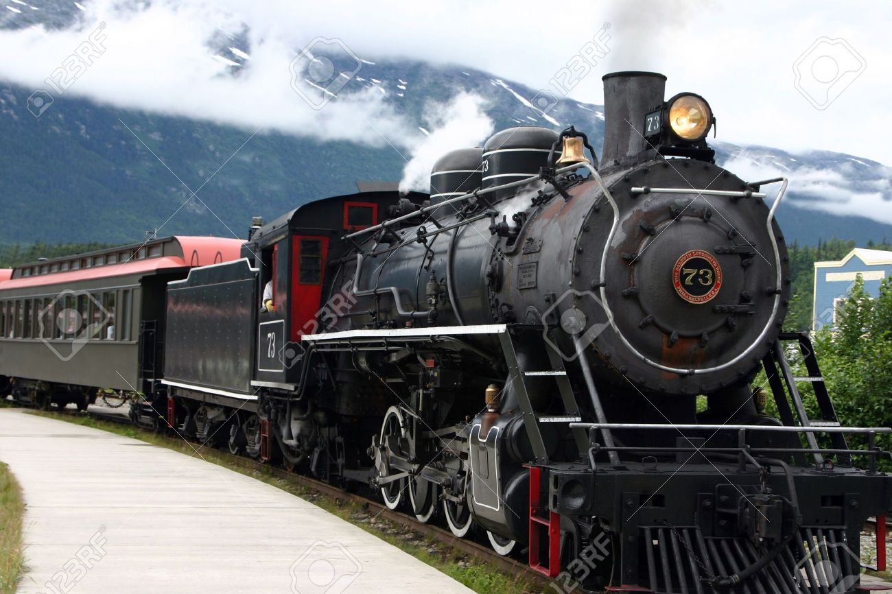 steam engine train leaving the station full of tourists stock photo