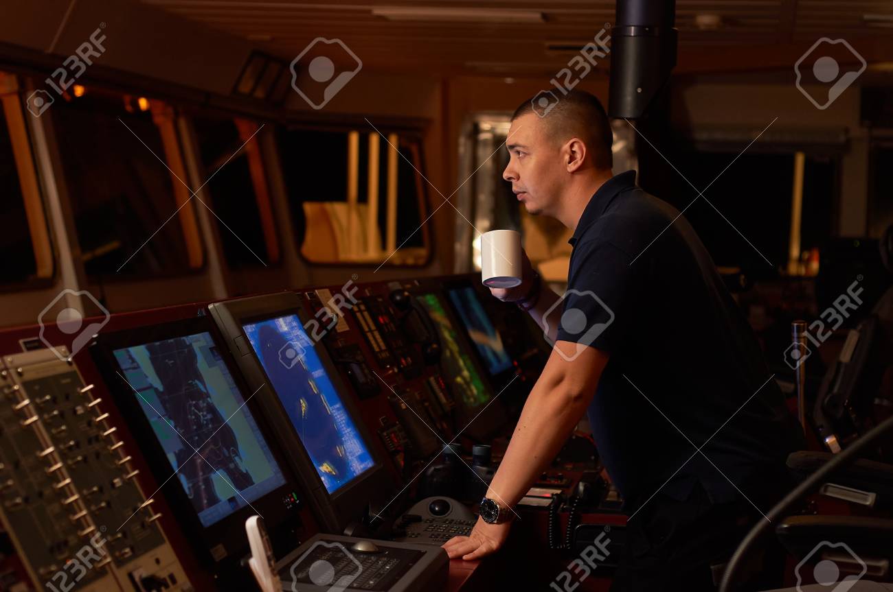 Navigation officer. Pilot on a bridge of a vessel underway with radio station and binocular in hands - 116416515 Navigation officer. Pilot on a bridge of a vessel underway with radio station and binocular in hands - 116416515