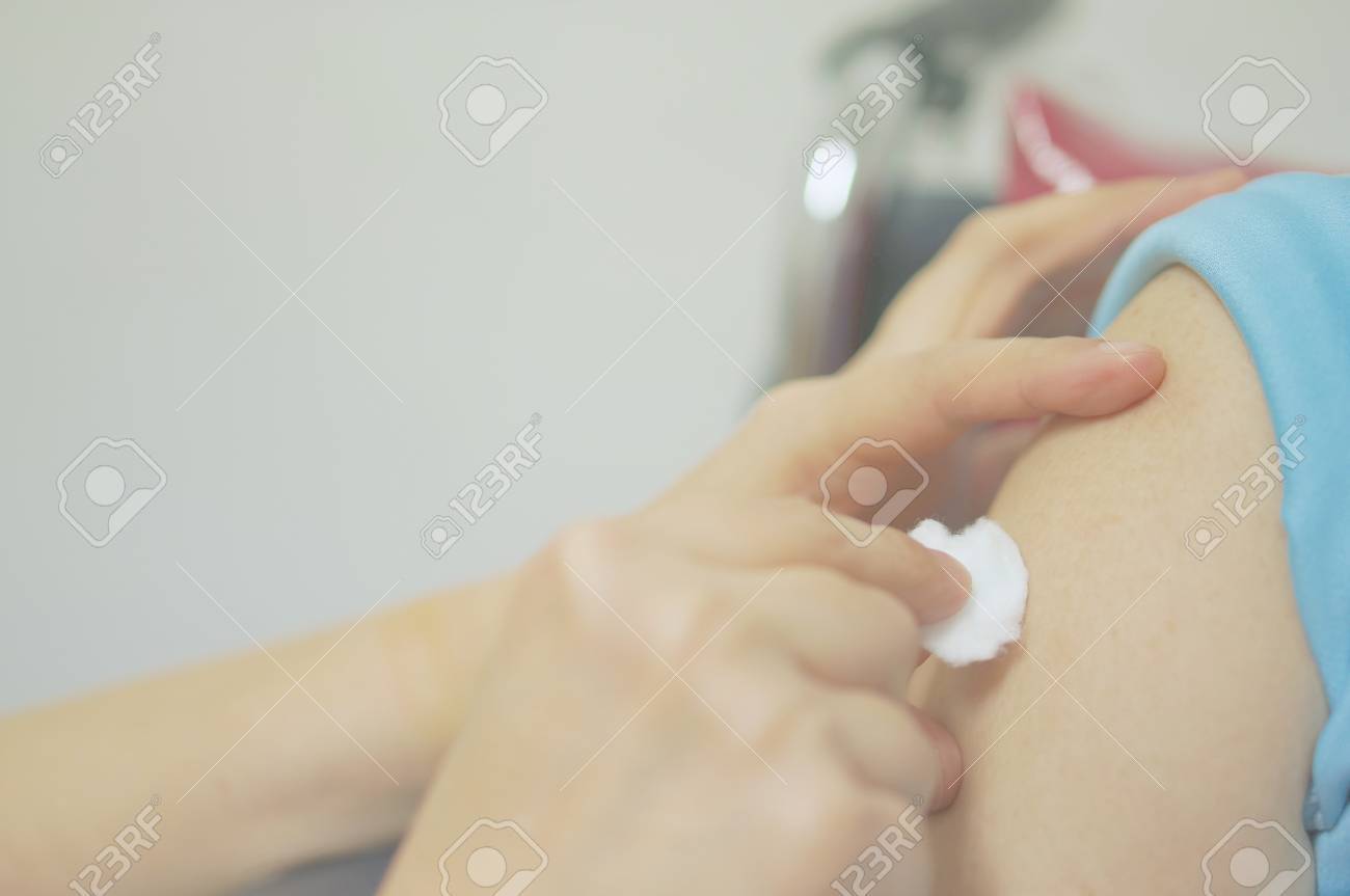 看護師の手は 白い背景を持つ車椅子にワクチンを注射するためのアルコールを用いたコットンボールによる患者の肌のクレンジングである の写真素材 画像素材 Image
