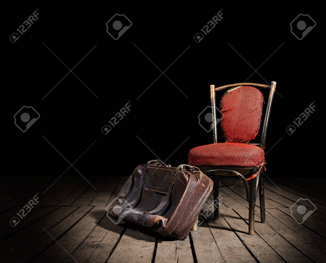 Old red chair and well,traveled vintage suitcase on wooden floor