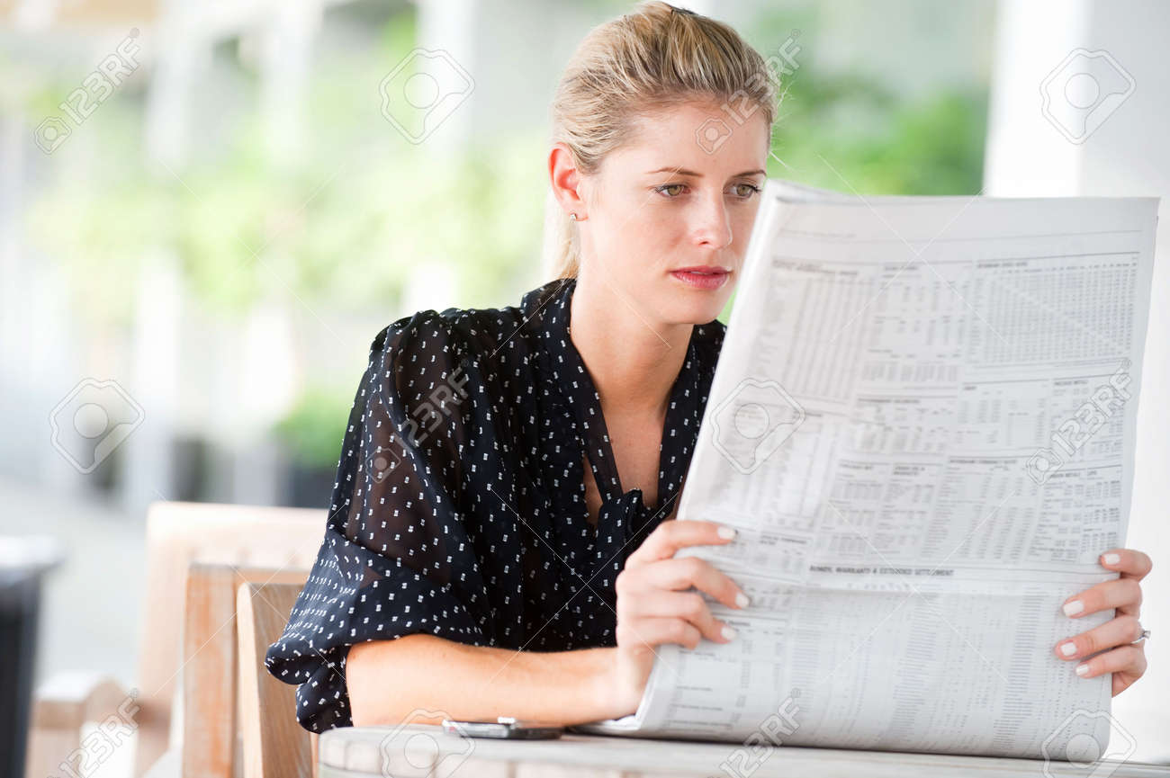 A young attractive woman reading newspapers at a cafeteria - 6338211 A young attractive woman reading newspapers at a cafeteria - 6338211