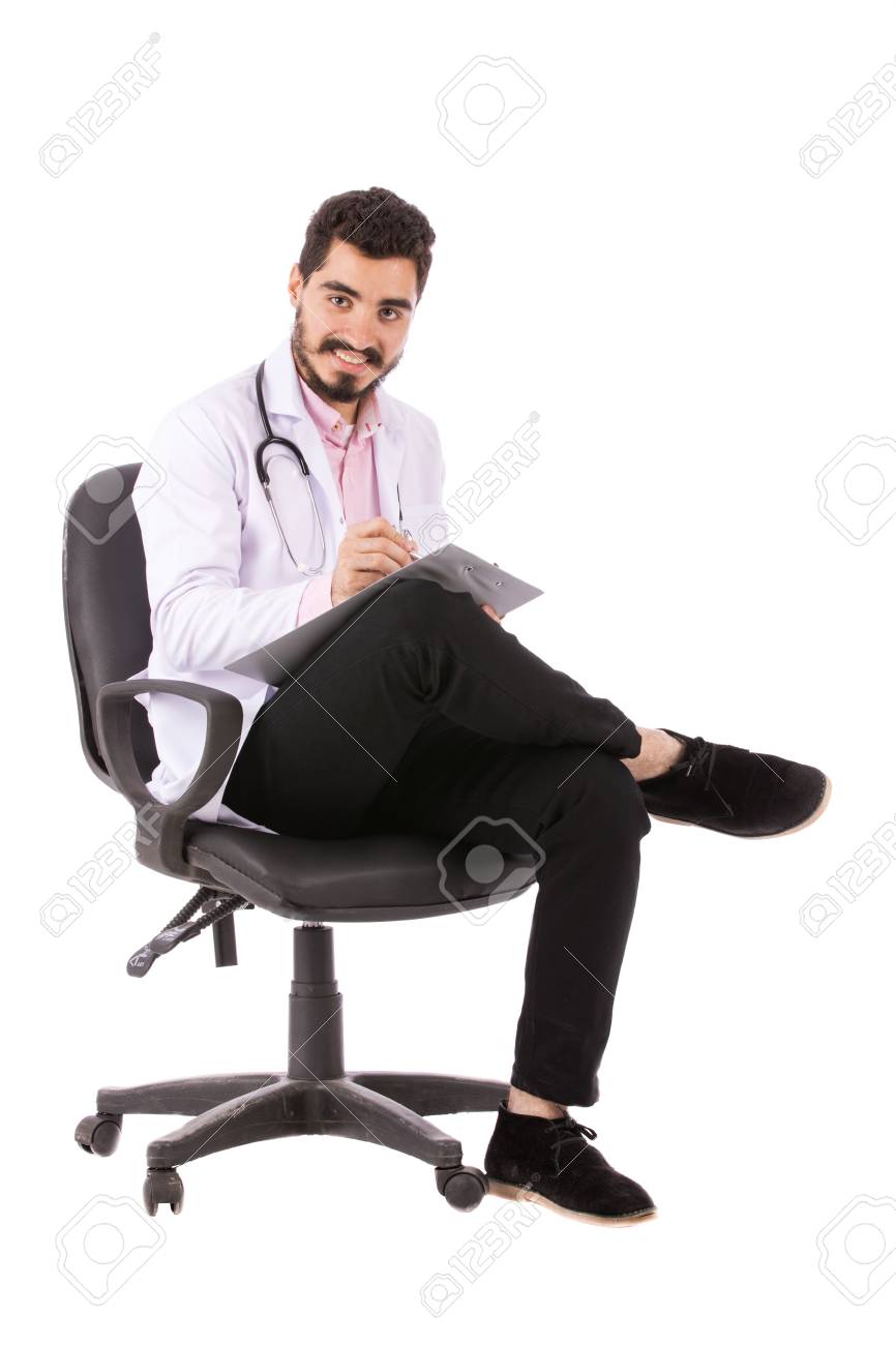 椅子に座っていると 白い背景上に分離されて いくつかのメモを取っては聴診器で白衣の若い医者を幸せなひげ の写真素材 画像素材 Image