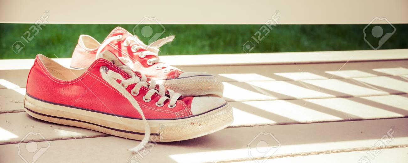 古い 汚いスニーカー デッキに座って一のパノラマ画像 靴の後ろから輝いている明るい日光から影を見ることができます の写真素材 画像素材 Image