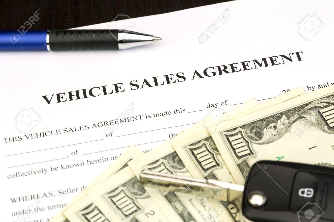 vehicle sales agreement document contract with car key and pen stock