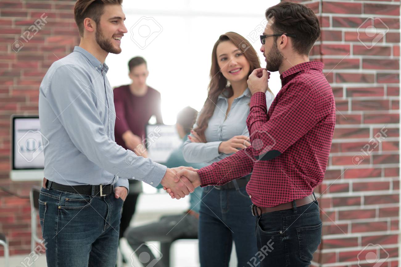 Smiling businessman shaking hands with colleague in office. - 93539329 Smiling businessman shaking hands with colleague in office. - 93539329