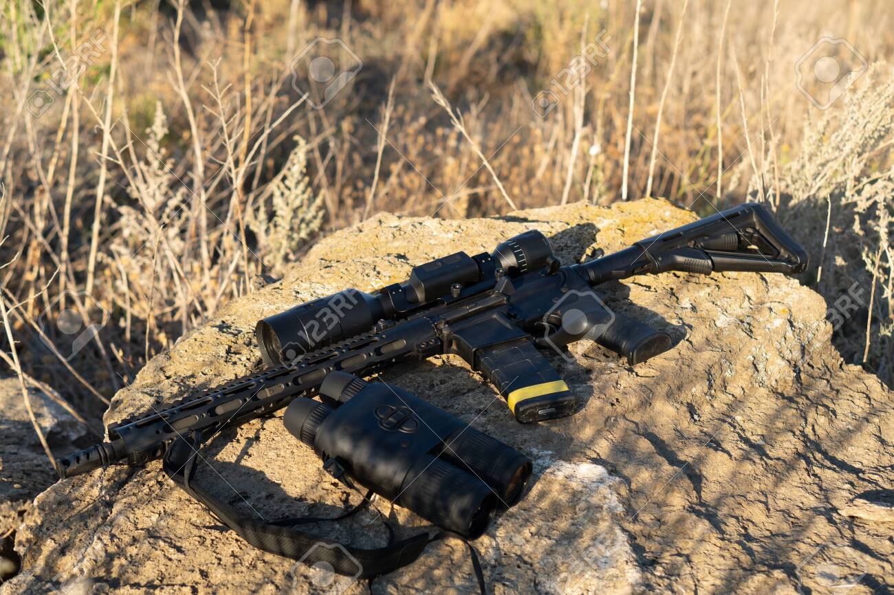 A rifle with a telescopic sight and binoculars on a stone background. Hunting and observation technologies - 155796838 A rifle with a telescopic sight and binoculars on a stone background. Hunting and observation technologies - 155796838