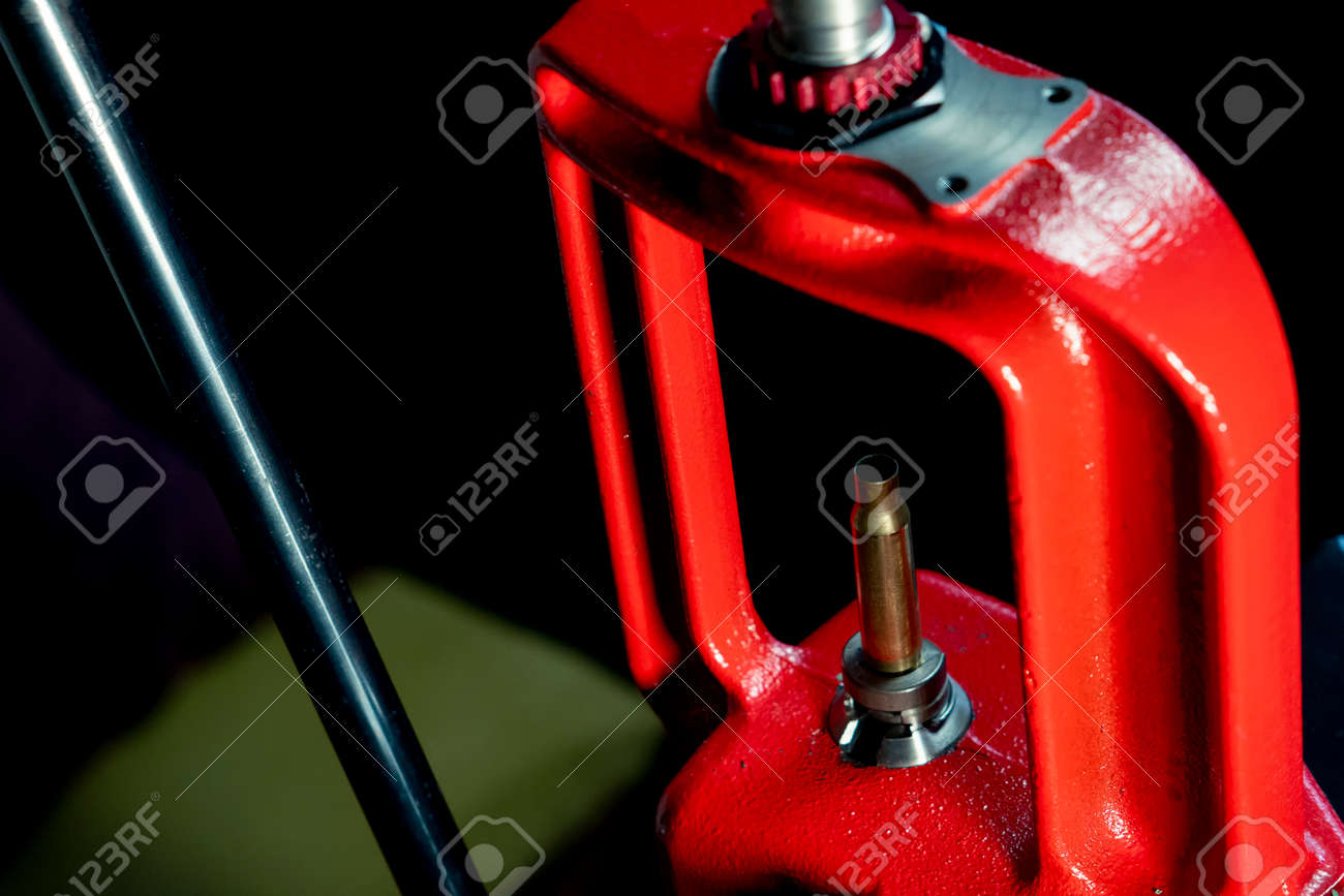 The process of making a rifle cartridge. Hand press and ammo shell against dark background, soft focus. Copy space - 163064634 The process of making a rifle cartridge. Hand press and ammo shell against dark background, soft focus. Copy space - 163064634