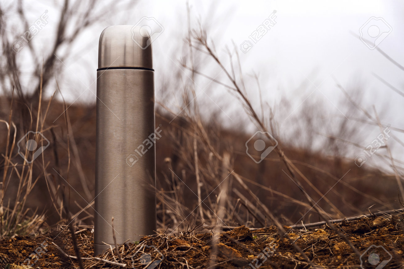 Steel vacuum flask with tea or coffee, outdoor. Hiking, active tourism, picnic, hot drink concept - 165799719 Steel vacuum flask with tea or coffee, outdoor. Hiking, active tourism, picnic, hot drink concept - 165799719