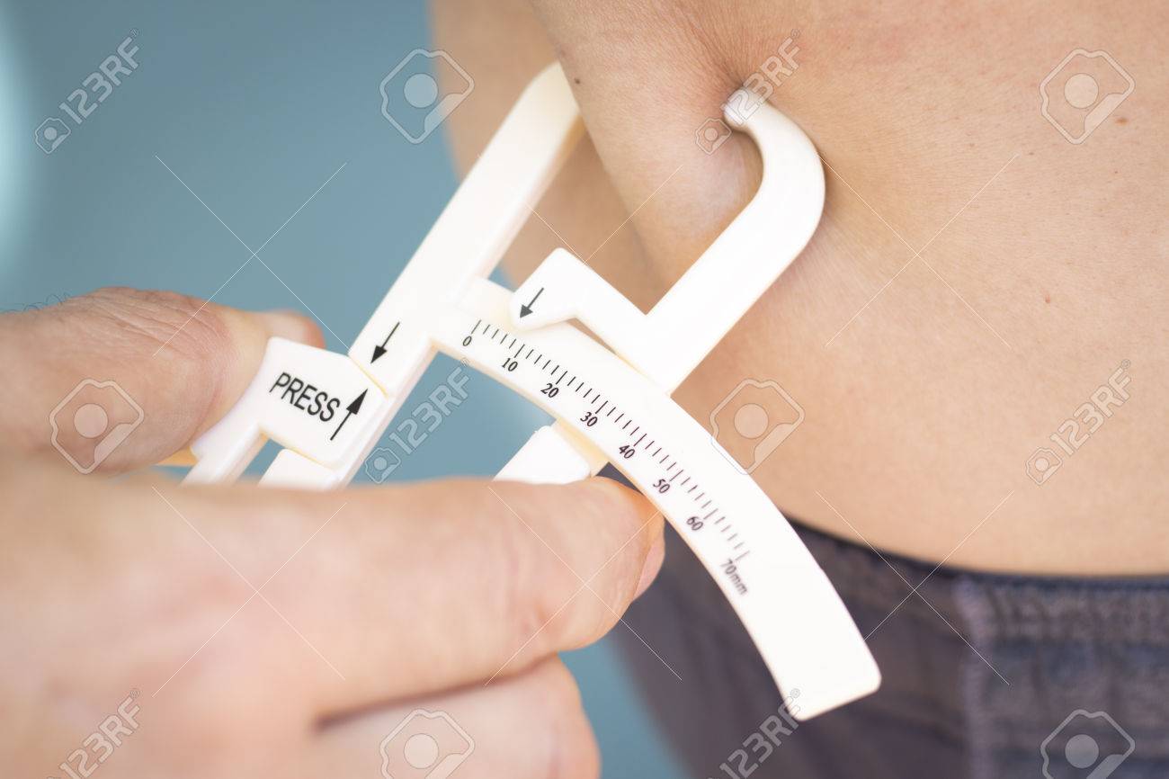 slim attractive young man using fat caliper to measure bodyfat caliper body fat