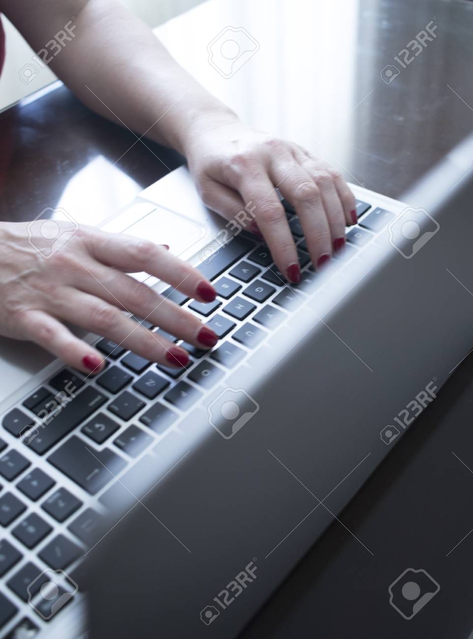 Secretary typist typing on laptop pc computer keyboard keys with hands with red nail varnish.