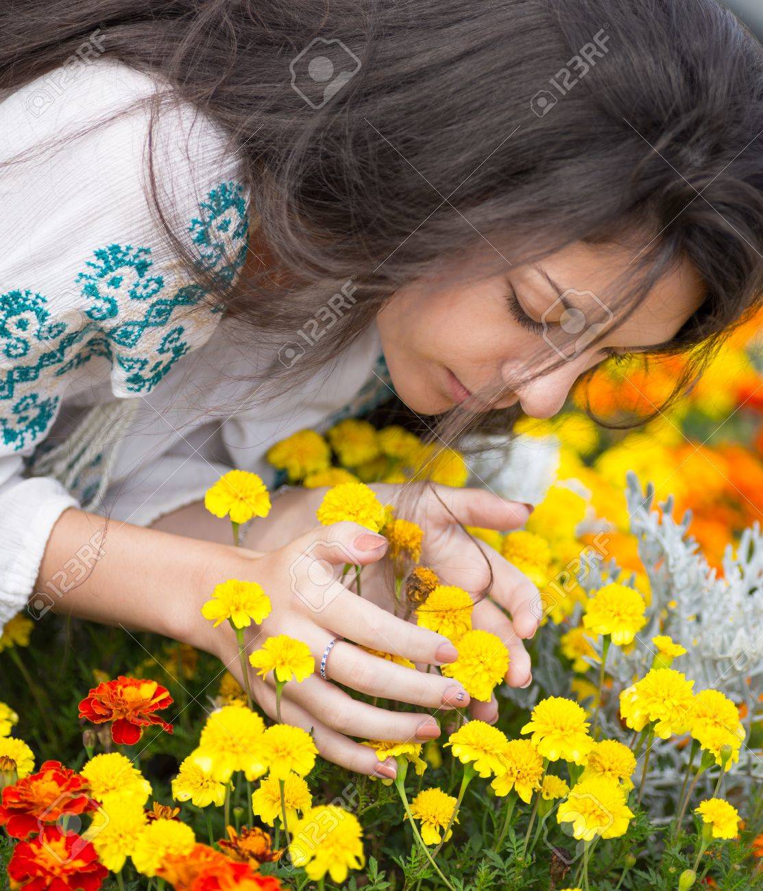 庭の黄色の花の臭いがする若い美しい女性 の写真素材 画像素材 Image