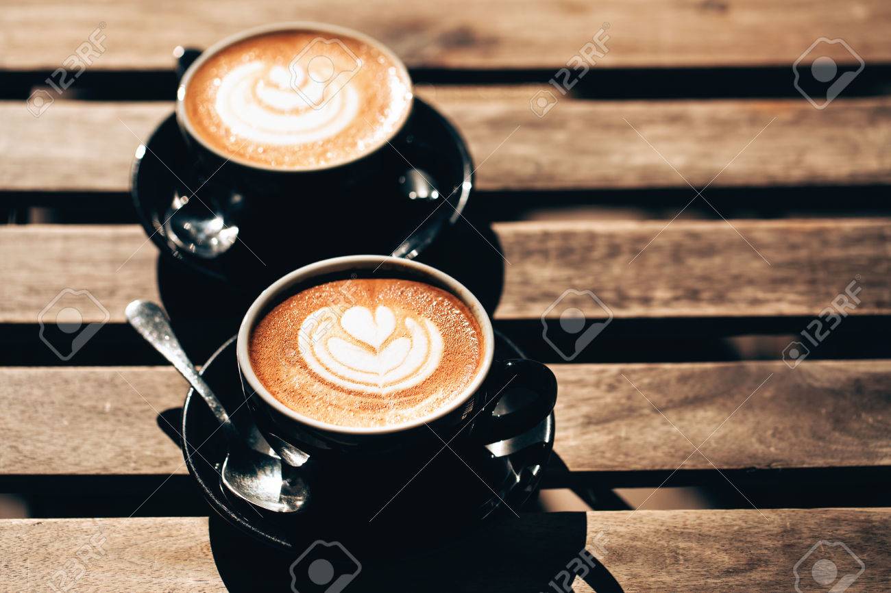 木製のテーブルに黒いカップでラテアート カプチーノ 2 杯 愛のカップルのためのモーニング コーヒー 平面図です の写真素材 画像素材 Image