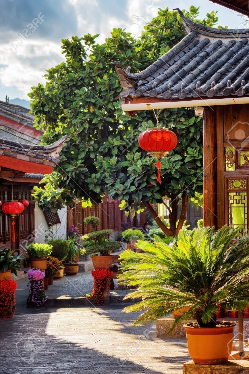 Scenic View Of Traditional Chinese Wooden Houses Decorated With Red Lanterns  On Narrow Street In The Old Town Of Lijiang, Yunnan Province, China.  Lijiang Is A Popular Tourist Destination Of Asia. Stock, image size:867x1300