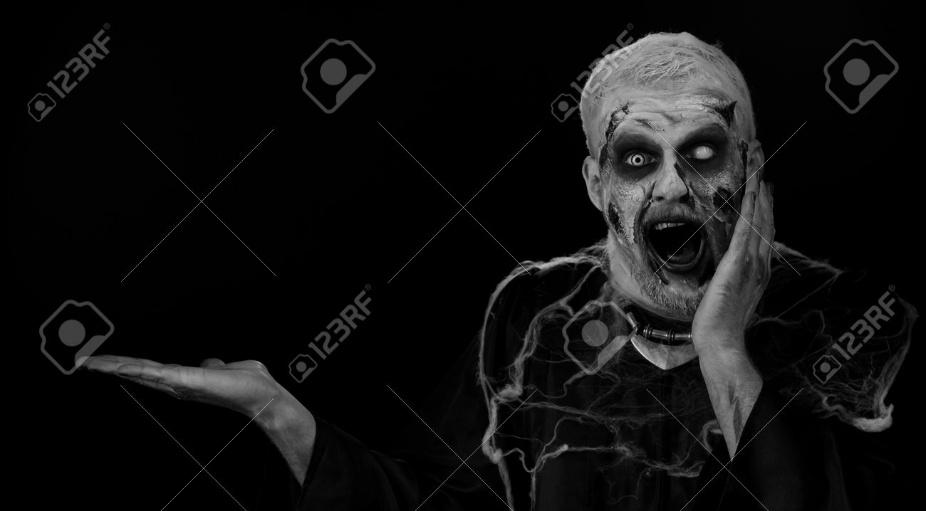 와우 놀람. 가짜 상처를 입은 좀비 남자는 엄지손가락을 치켜들고 빈 곳을 가리키며 상업 텍스트 로고를 위한 광고 영역, 상품 판촉을  위한 복사 공간을 만듭니다. 할로윈 못생긴 죽은 남자 로열티 무료 사진, 그림,