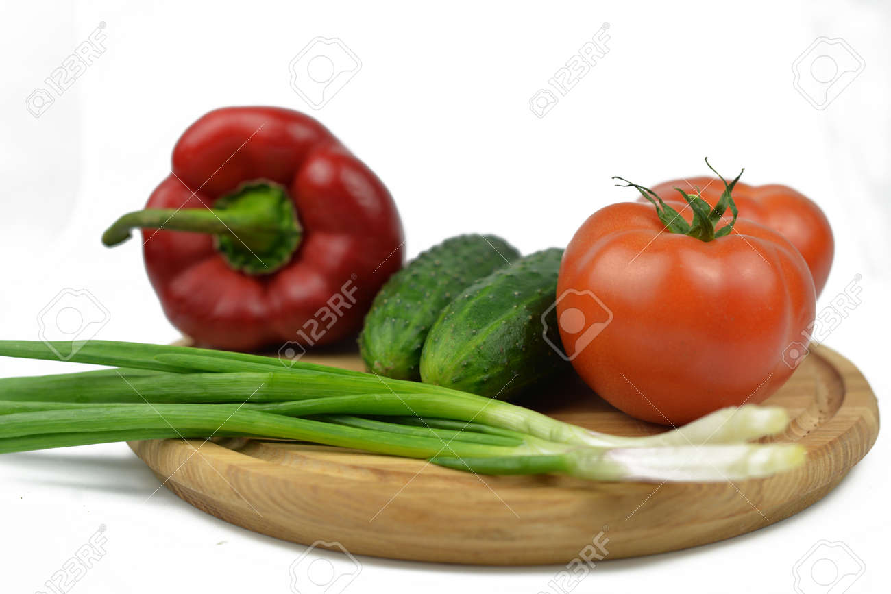 board on a wooden board vegetables with green onions tomatoes red paprika peppers green cucumbers and diet vitamins on a white isolated background - 163505590 board on a wooden board vegetables with green onions tomatoes red paprika peppers green cucumbers and diet vitamins on a white isolated background - 163505590