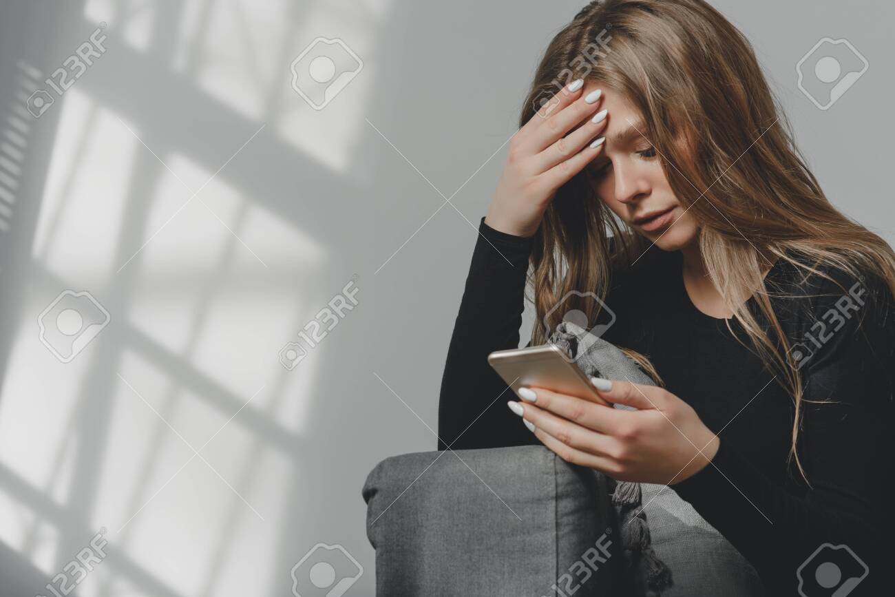 Portrait Of A Young Sad Crying Girl With A Smartphone In Her Hand ...