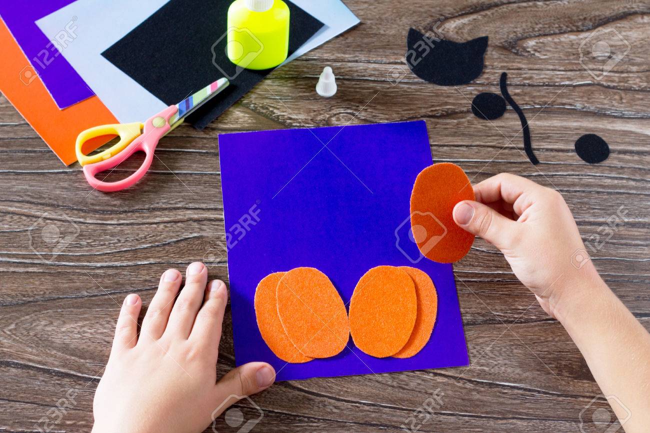 子供は 紙のパーツを貼り付け カボチャのグリーティング カード ハロウィン黒紙猫を作成します のり はさみ 木のテーブルにビロードの紙を残します 子どものアート プロジェクト 子供のための工芸品 の写真素材 画像素材 Image