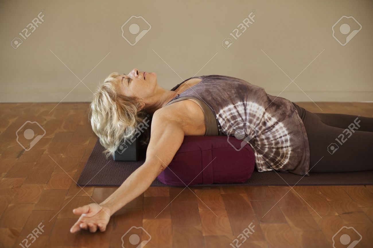 Middle age woman resting on a yoga bolster. - 9189848 Middle age woman resting on a yoga bolster. - 9189848