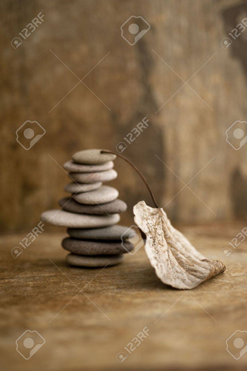 Stacked stones and a fallen leaf in a earth toned setting - 15512580 Stacked stones and a fallen leaf in a earth toned setting - 15512580