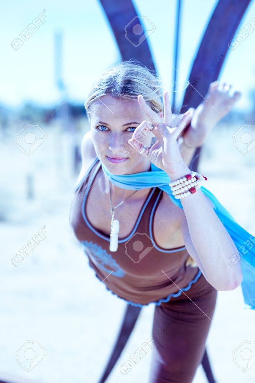 Blue toned artistic photograph of a woman in yoga Natarajasana or Dancer's Pose in front of some abstract shapes with a yogic hand mudra held near her blue eye. - 15508474 Blue toned artistic photograph of a woman in yoga Natarajasana or Dancer's Pose in front of some abstract shapes with a yogic hand mudra held near her blue eye. - 15508474