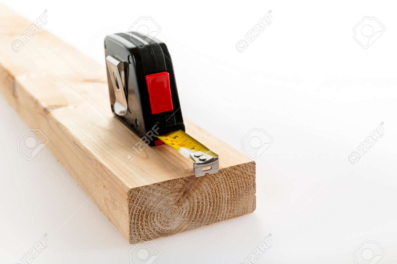 Metal imperial metric tape measure measuring two by four lumber on white background - 29611454 Metal imperial metric tape measure measuring two by four lumber on white background - 29611454