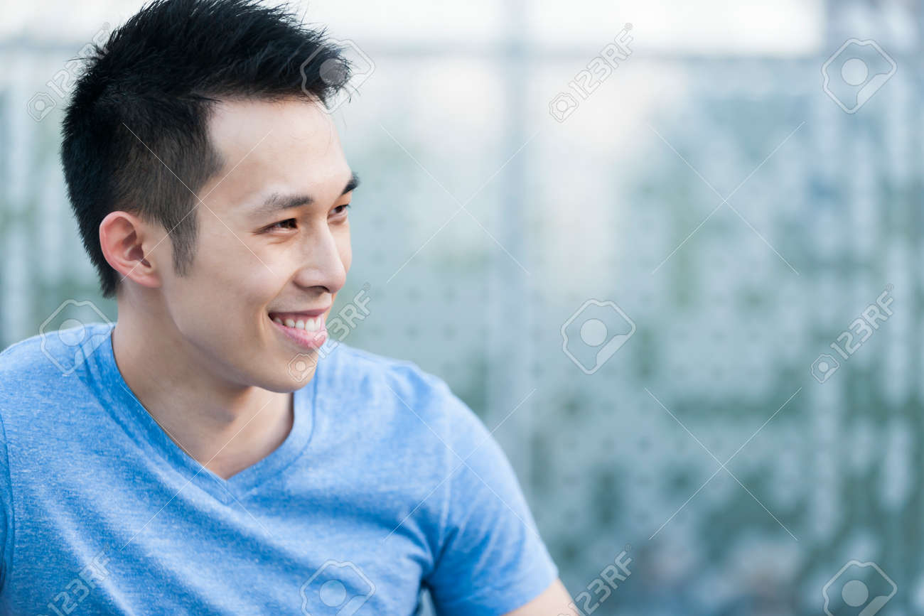 Portrait of confident young asian man in profile smiling on blue background with copy space - 31947592 Portrait of confident young asian man in profile smiling on blue background with copy space - 31947592