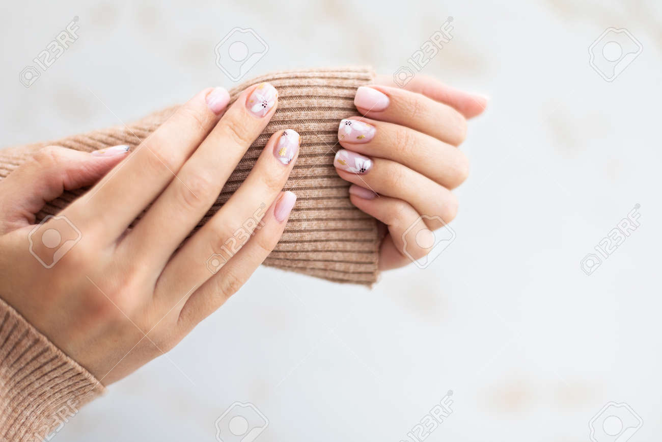 Pastel beige manicure on the light background. Manicured nails and soft hands skin with copy space. Womans hands in warm sweater. - 165834164 Pastel beige manicure on the light background. Manicured nails and soft hands skin with copy space. Womans hands in warm sweater. - 165834164