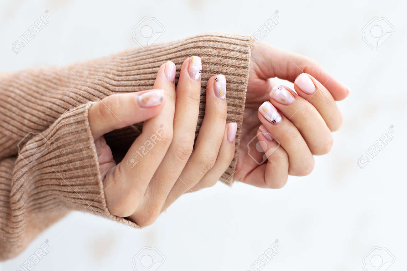 Pastel beige manicure on the light background. Manicured nails and soft hands skin with copy space. Womans hands in warm sweater. - 166315522 Pastel beige manicure on the light background. Manicured nails and soft hands skin with copy space. Womans hands in warm sweater. - 166315522