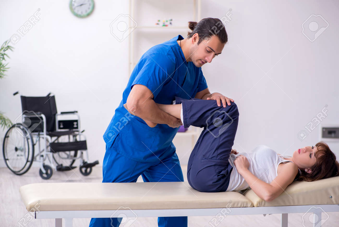 Injured woman visiting young male doctor osteopath - 149914736 Injured woman visiting young male doctor osteopath - 149914736