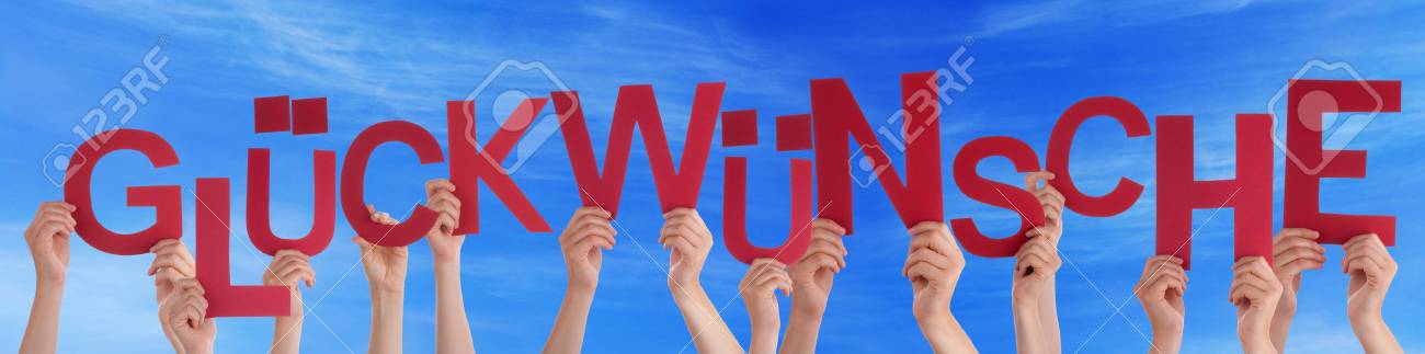 多くの白人の人々 と赤い文字や文字建物おめでとうございます青空を意味するドイツ語の単語 Glueckwuensche を保持している手 の写真素材 画像素材 Image