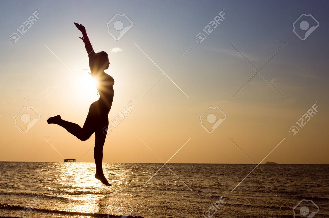 幸せな女性は ビーチでジャンプ 海の夕日 の写真素材 画像素材 Image