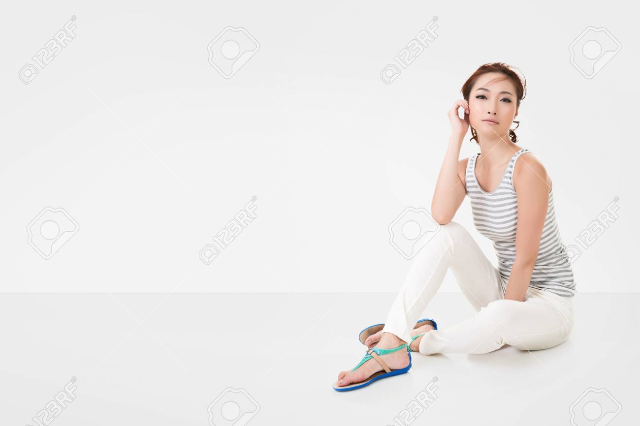 魅力的なアジアの女性は白い壁の Copyspace を持つ完全な長さの肖像画 地面に座る の写真素材 画像素材 Image