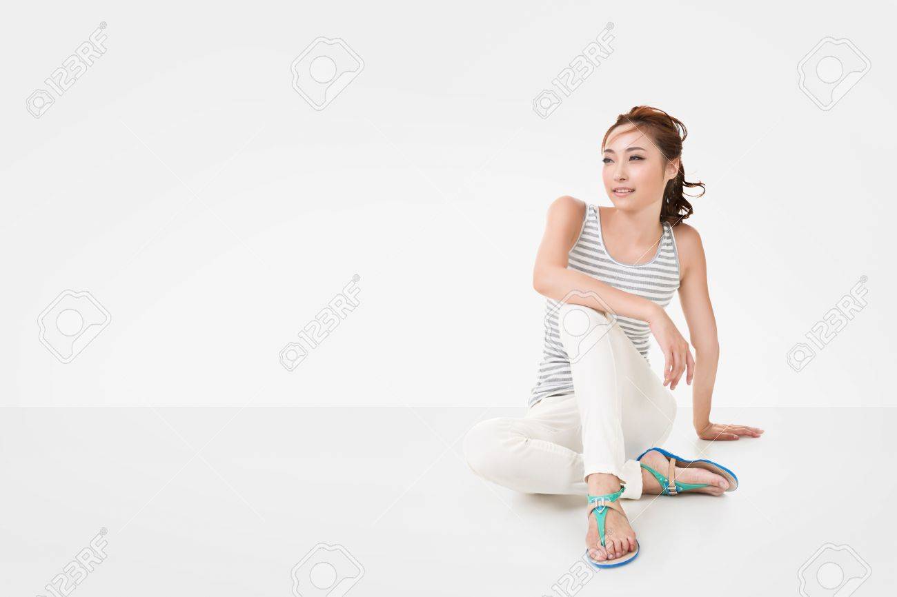魅力的なアジアの女性は白い壁の Copyspace を持つ完全な長さの肖像画 地面に座る の写真素材 画像素材 Image