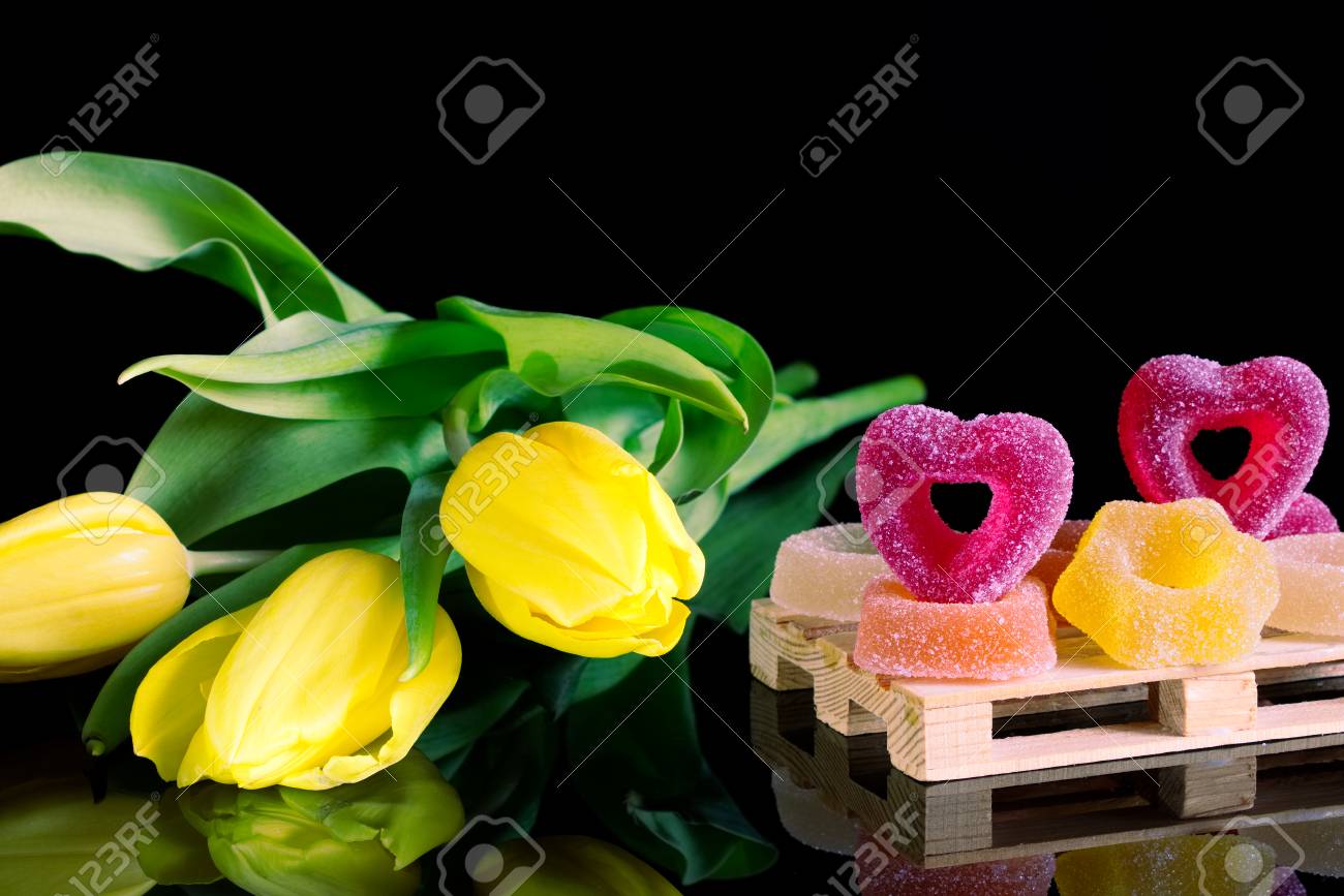 Bonbons Sucrés Romantiques Et Un Bouquet De Tulipes Jaunes Gelée De Bonbons Avec Des Fleurs Comme Un Cadeau Sur Un Fond Noir