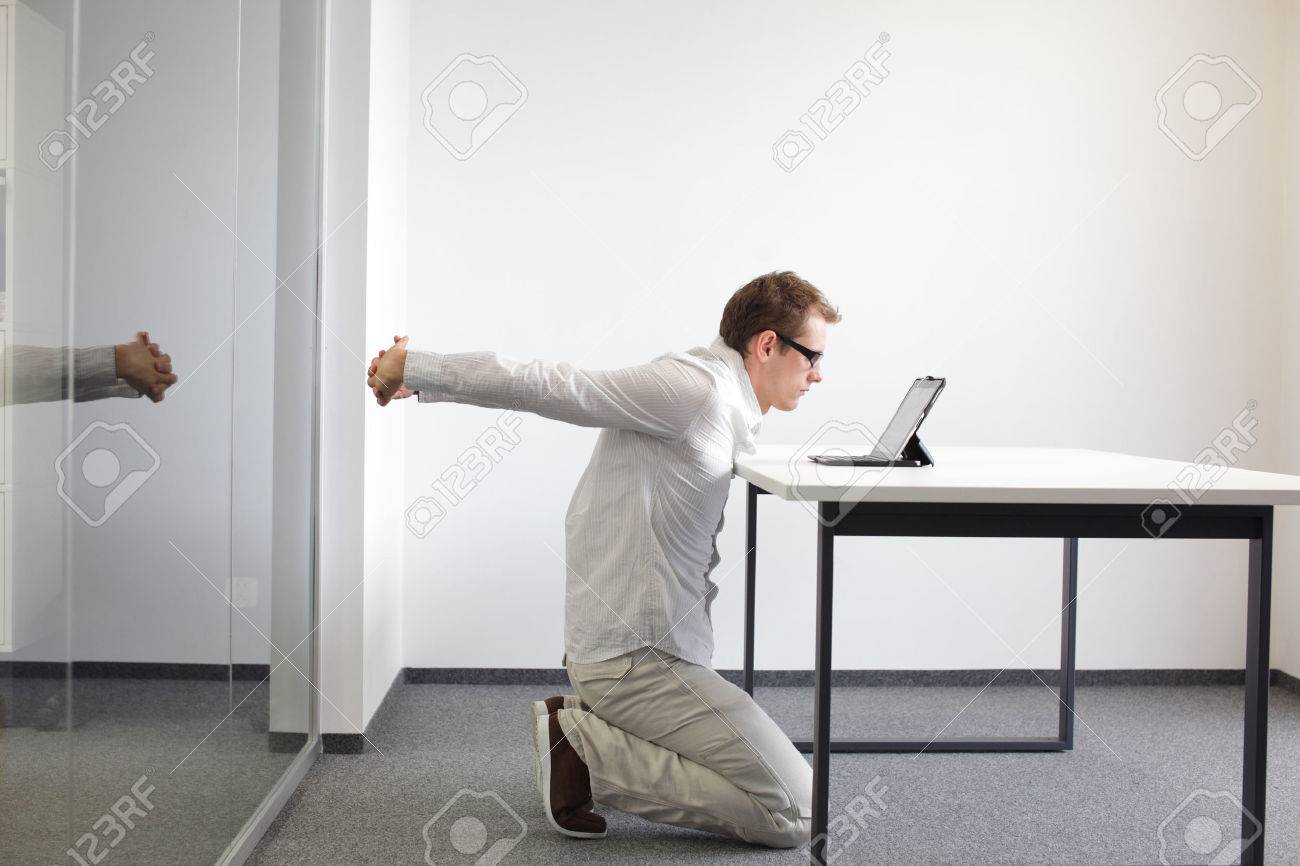 arms stretching - man doing exercises during work with tablet in his office - 26624203 arms stretching - man doing exercises during work with tablet in his office - 26624203