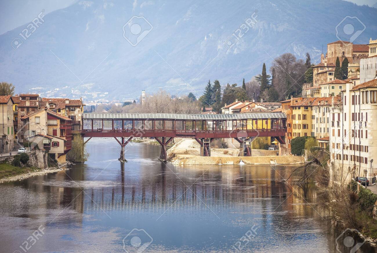 Bridge Ponte degli Alpini at river Brenta in Bassano del Grappa, Italy. Panoramic view at old town with vintage building and wooden bridge - 147193802 Bridge Ponte degli Alpini at river Brenta in Bassano del Grappa, Italy. Panoramic view at old town with vintage building and wooden bridge - 147193802