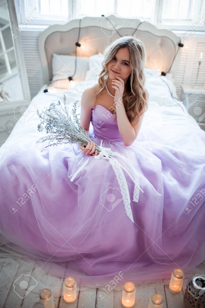 Una Joven Novia Rubia En Un Magnifico Vestido Morado Sentado En La Cama En Las Velas De La Habitacion Chica Tiene En Las Manos Del Disenador Ramo De Plata Fotos Retratos Imagenes