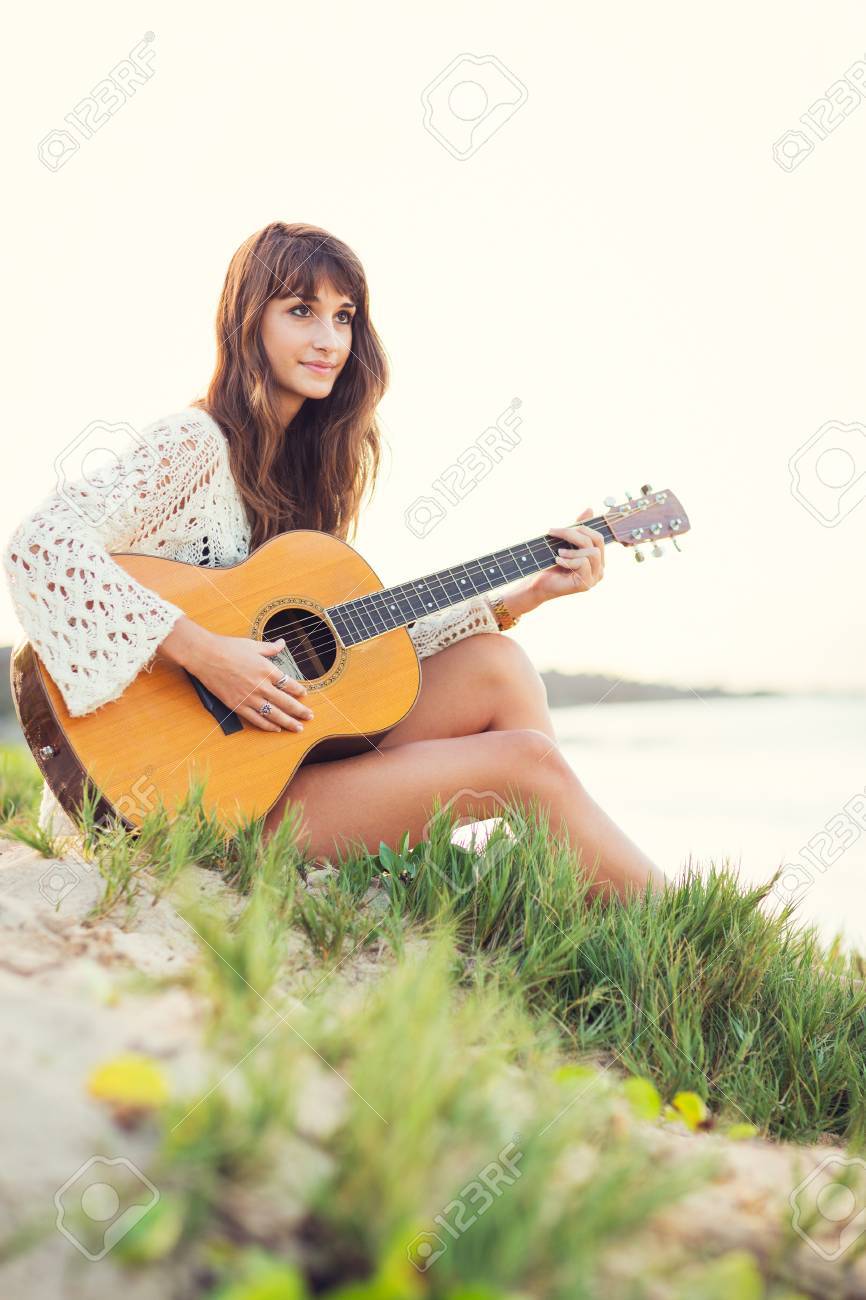 美しい若い女性のビーチでサンセット ファッション ライフ スタイルでギターを弾く の写真素材 画像素材 Image