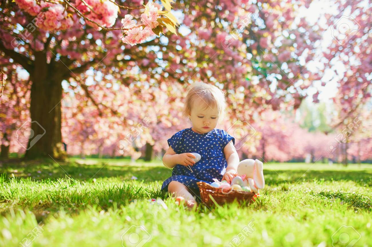 Cute Little One Year Old Girl Playing Egg Hunt On Easter Toddler Sitting On The Grass