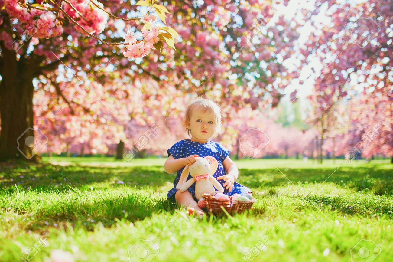 Cute Little One Year Old Girl Playing Egg Hunt On Easter Toddler Sitting On The Grass