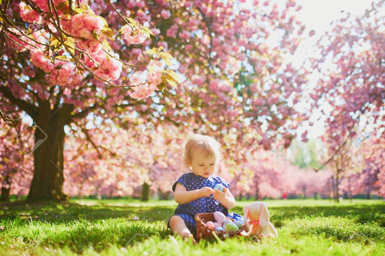 Cute Little One Year Old Girl Playing Egg Hunt On Easter Toddler Sitting On The Grass