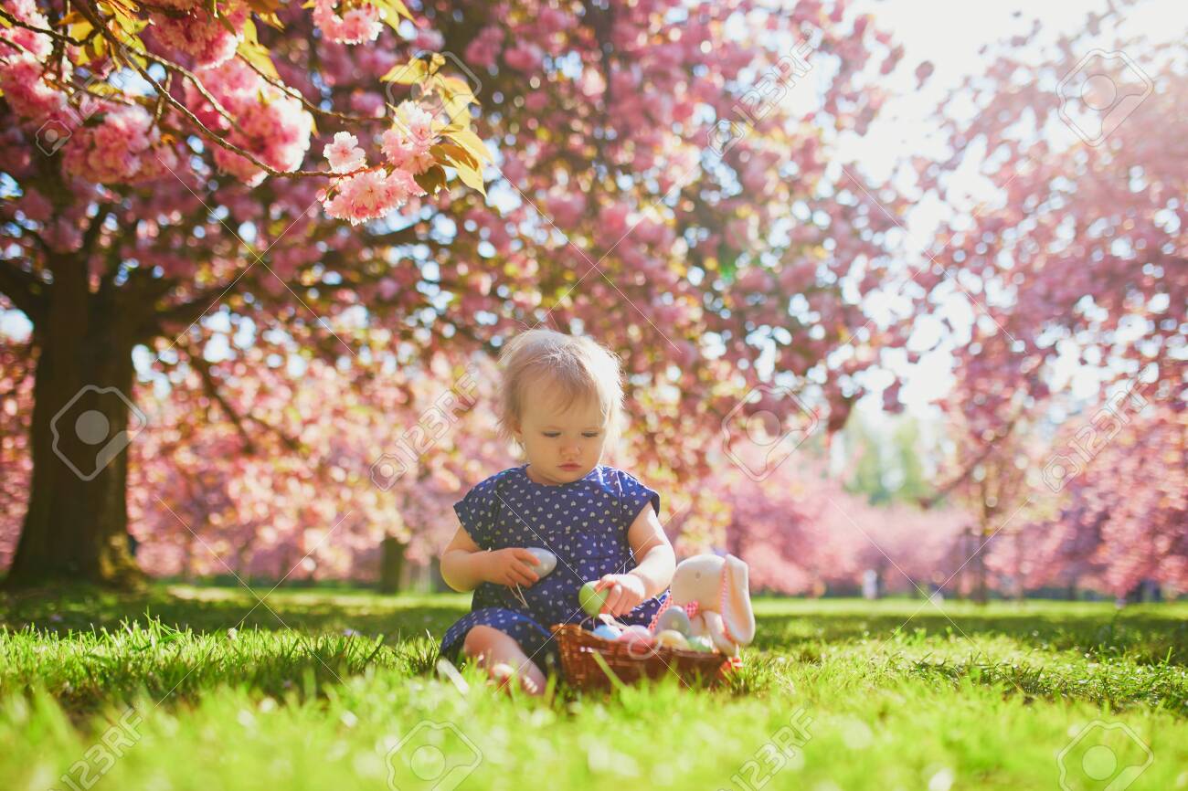 Cute Little One Year Old Girl Playing Egg Hunt On Easter Toddler Sitting On The Grass